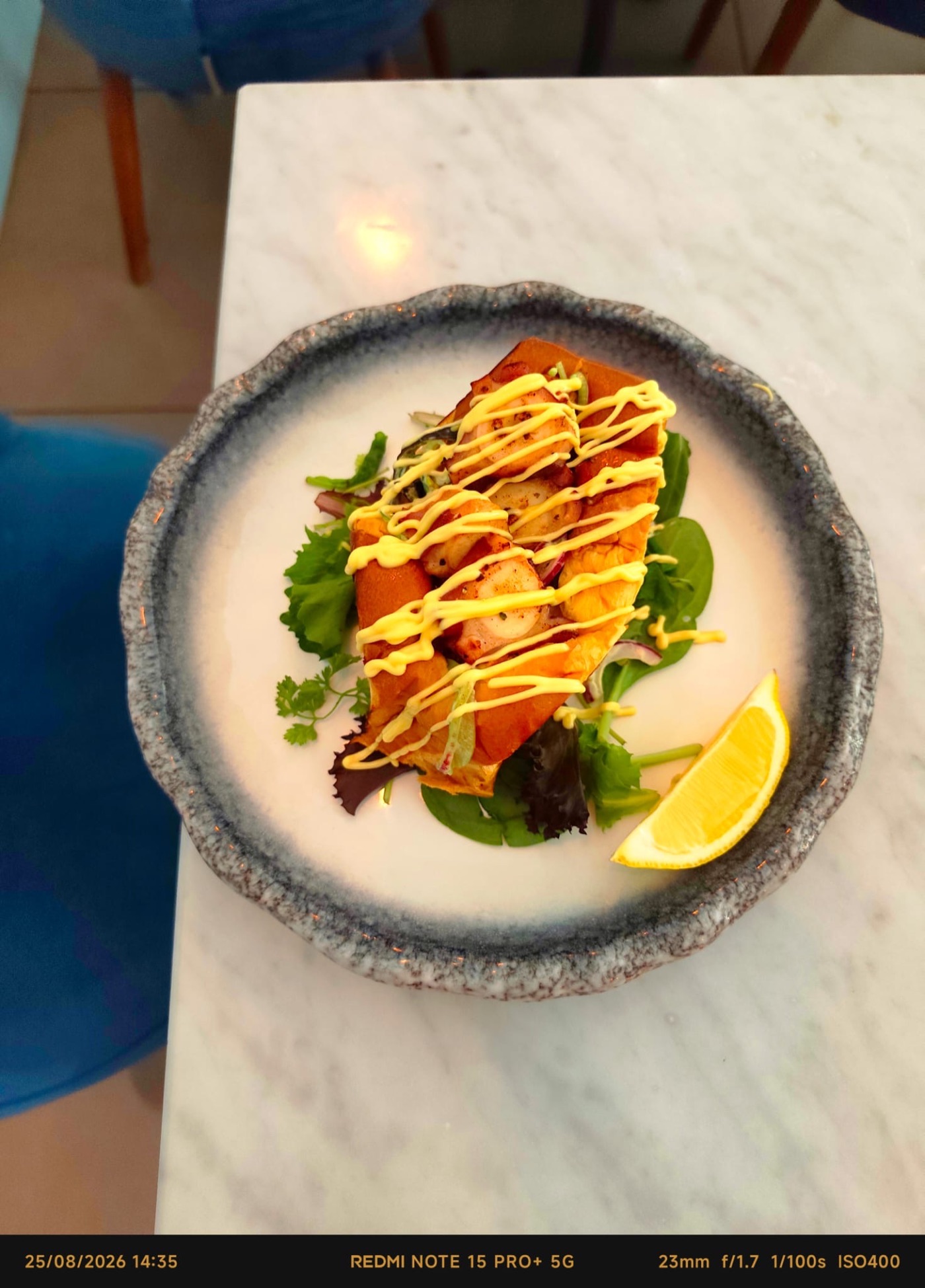 Sandwich au poulpe grillé, aïoli au citron et salade fraîche, servi sur une assiette en céramique chez MIKI